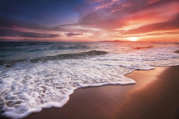 Le onde su una spiaggia deserta al tramonto, in Thailandia